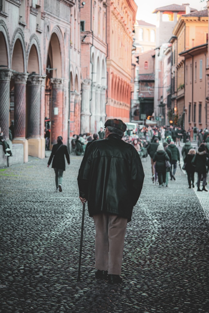 An older man on an evening stroll with his cane in Bologna, Italy March 2024