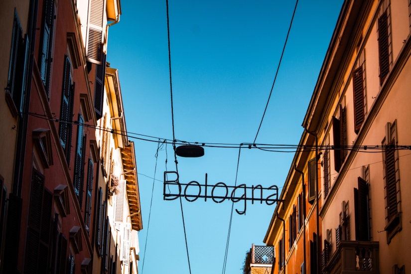 A neon sign reading "Bologna" strung between two buildings in Bologna, Italy March 2024