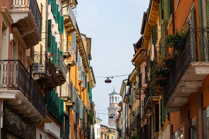 Building with balconies, green shutters, and plants in Verona, Italy, March 2024.