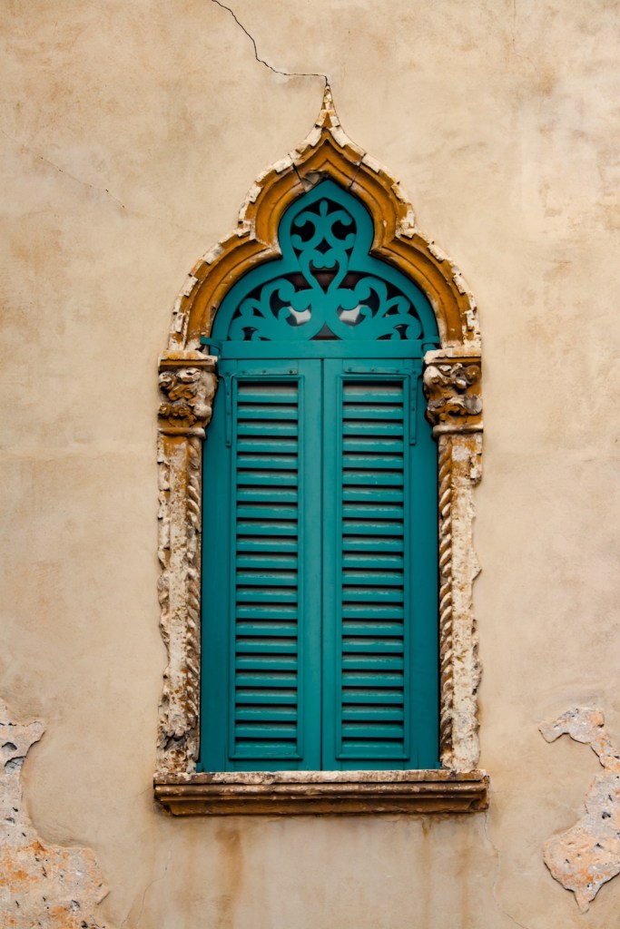 worn blue window shutters in Verona, Italy, March 2024